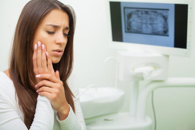 Young female having toothache. Upset woman at the dentist. Constant pulsating pain