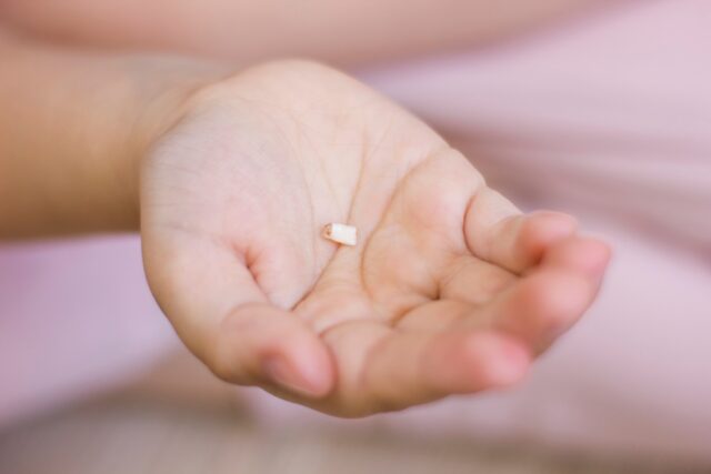 Closeup kids hand with milk tooth. First tooth lost.