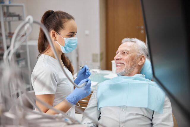 Elderly man looking at his skillful female dentist